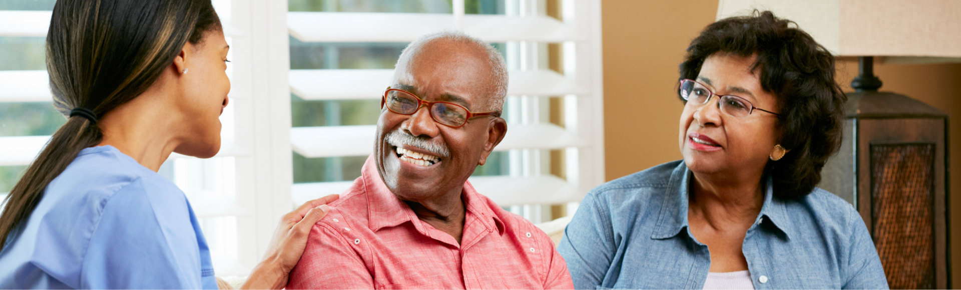 caregiver and elderly couple both smiling